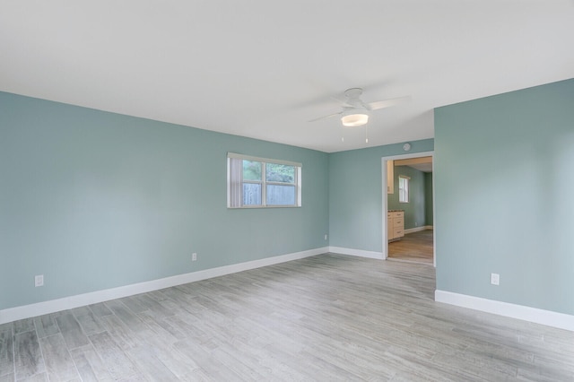 empty room with ceiling fan and light hardwood / wood-style flooring