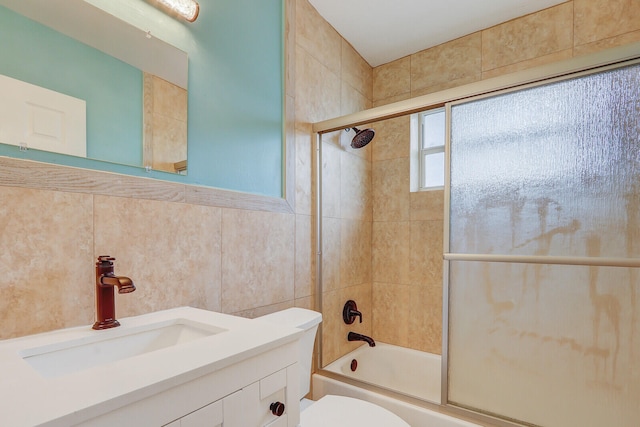 full bathroom featuring tile walls, shower / bath combination with glass door, vanity, and toilet