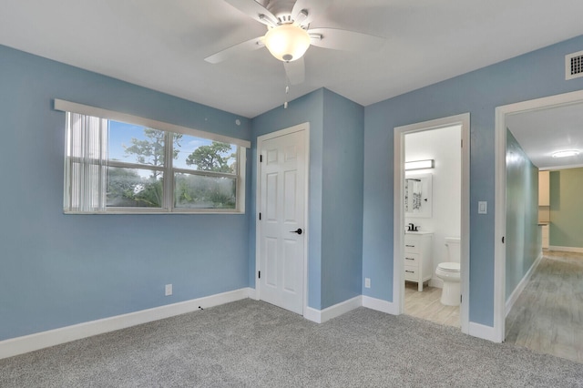 unfurnished bedroom featuring light colored carpet, ceiling fan, and ensuite bathroom