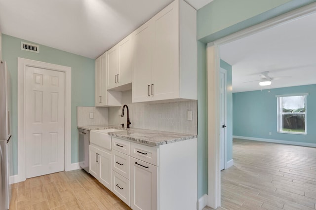 kitchen with ceiling fan, white cabinets, sink, backsplash, and light wood-type flooring