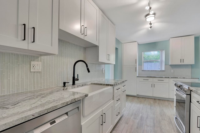 kitchen featuring light wood-type flooring, light stone counters, white cabinetry, stainless steel appliances, and backsplash