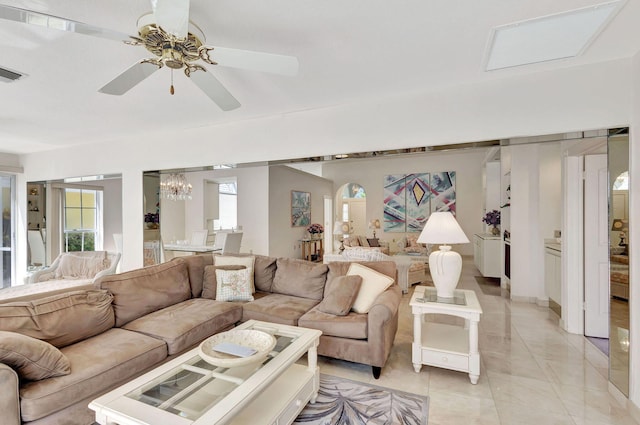 living room with light tile patterned flooring and ceiling fan with notable chandelier