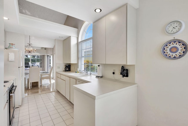 kitchen featuring a chandelier, sink, white cabinets, light tile patterned floors, and black stove