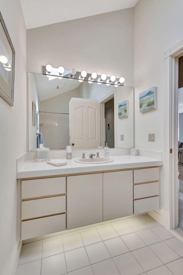 bathroom with tile patterned flooring, vaulted ceiling, and vanity