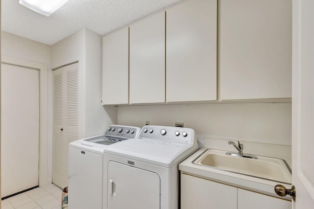 laundry area featuring cabinets, a textured ceiling, sink, light tile patterned floors, and washer and clothes dryer