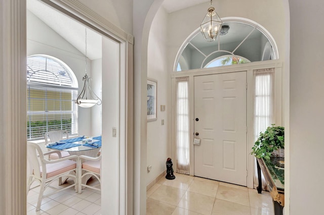 tiled foyer entrance featuring lofted ceiling and a chandelier