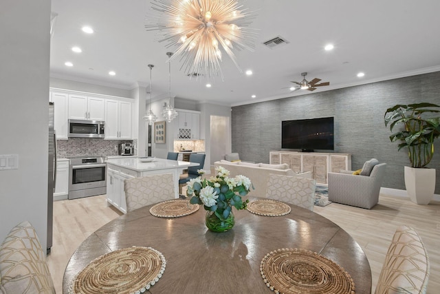 dining area featuring ceiling fan with notable chandelier, light hardwood / wood-style floors, and crown molding