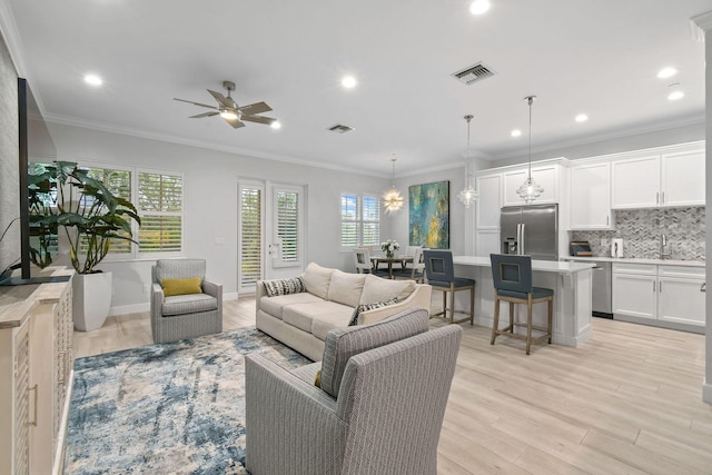 living room featuring sink, light wood-type flooring, ceiling fan, and ornamental molding