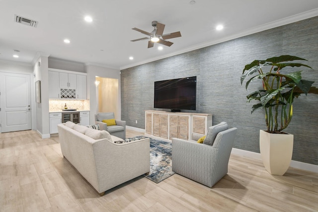 living room featuring beverage cooler, bar, light wood-type flooring, ceiling fan, and crown molding