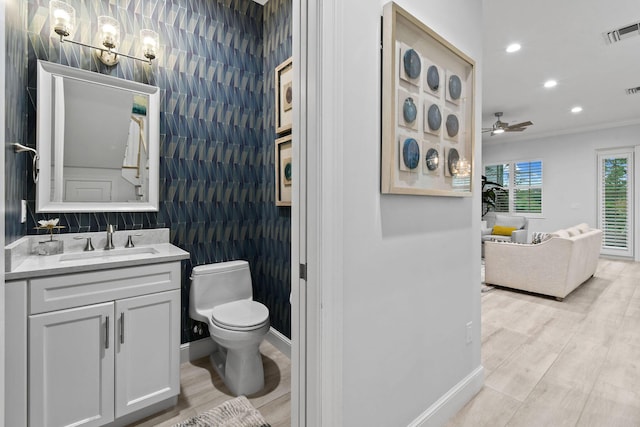 bathroom with toilet, crown molding, tile walls, vanity, and ceiling fan