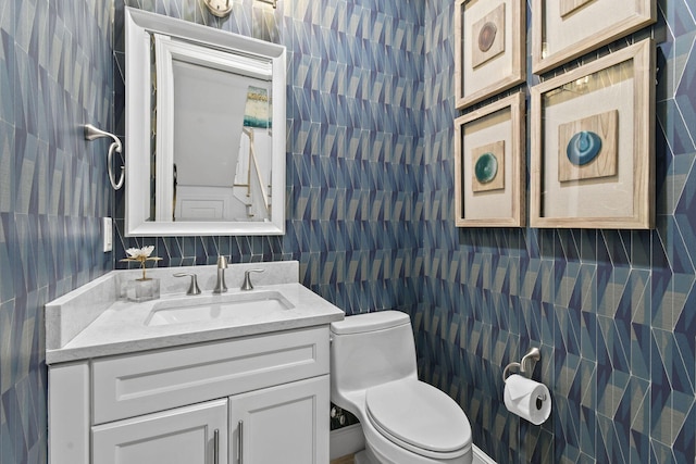 bathroom with vanity, toilet, and tile walls