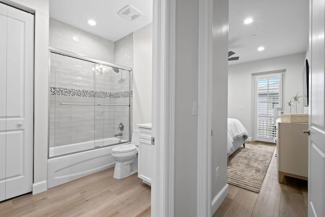 full bathroom with hardwood / wood-style floors, toilet, combined bath / shower with glass door, and vanity