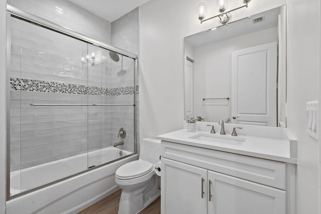 full bathroom featuring hardwood / wood-style floors, toilet, shower / bath combination with glass door, and vanity