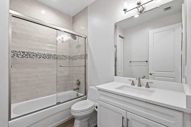 full bathroom featuring shower / bath combination with glass door, vanity, and toilet