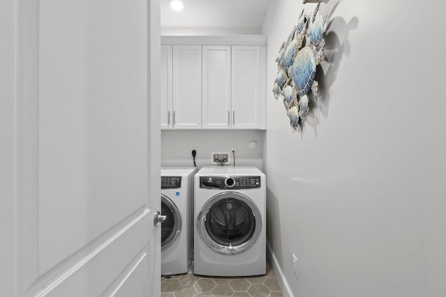 washroom featuring cabinets, washing machine and dryer, and light tile patterned flooring