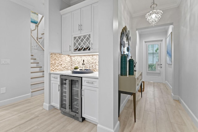 interior space with decorative light fixtures, white cabinetry, decorative backsplash, a chandelier, and beverage cooler