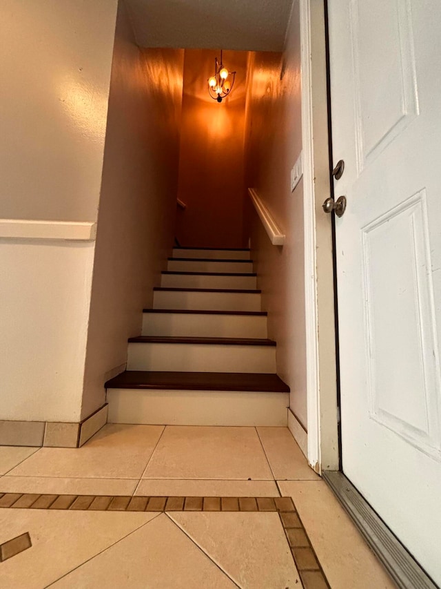 staircase featuring a notable chandelier and tile patterned floors