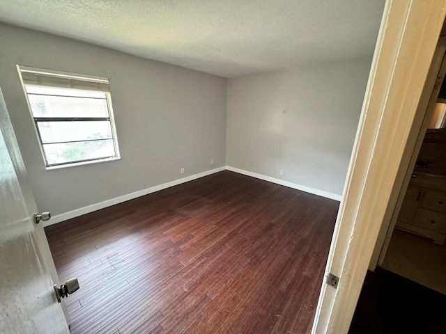 unfurnished room featuring a textured ceiling and dark wood-type flooring