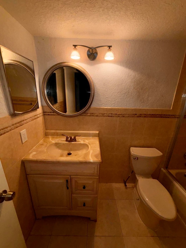 full bathroom with tile walls, a textured ceiling, tile patterned floors, vanity, and toilet