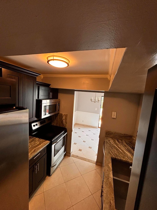 kitchen with stainless steel appliances, light stone counters, dark brown cabinetry, and crown molding