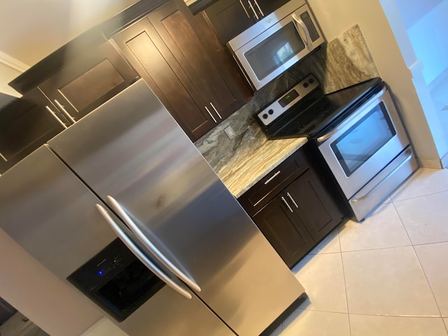 kitchen with dark brown cabinets, appliances with stainless steel finishes, and light tile patterned floors