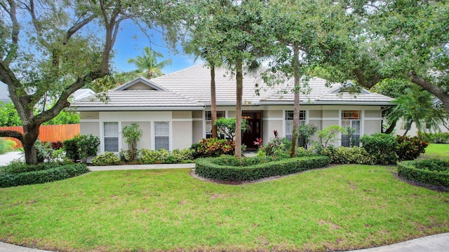 ranch-style home with stucco siding, a front yard, and a tile roof