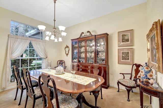 dining space with light colored carpet, a chandelier, and baseboards