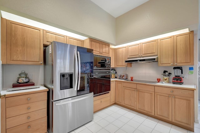 kitchen with light brown cabinets, under cabinet range hood, light countertops, black appliances, and backsplash