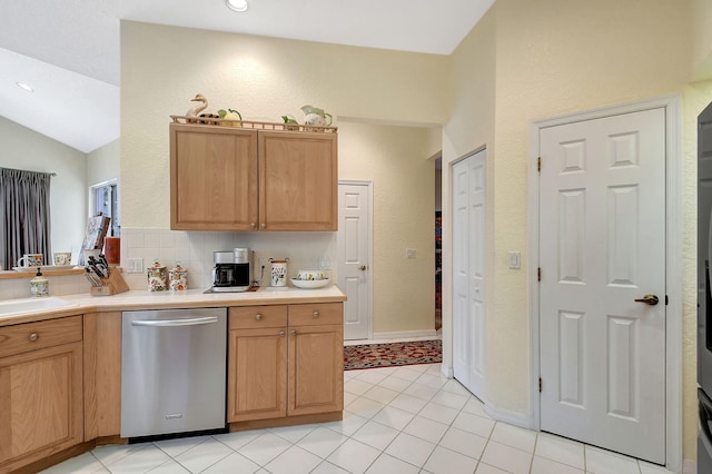 kitchen featuring a sink, light tile patterned flooring, light countertops, stainless steel dishwasher, and lofted ceiling