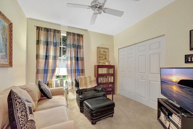 living area featuring a textured ceiling, light colored carpet, and ceiling fan