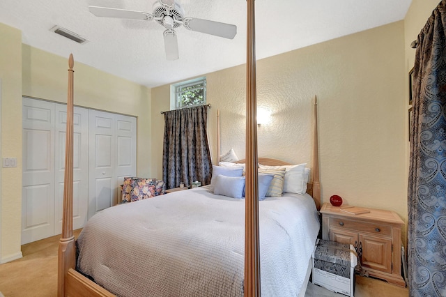 bedroom featuring a closet, ceiling fan, light carpet, and a textured ceiling