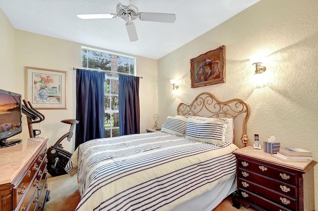 bedroom featuring a textured ceiling, light colored carpet, and ceiling fan