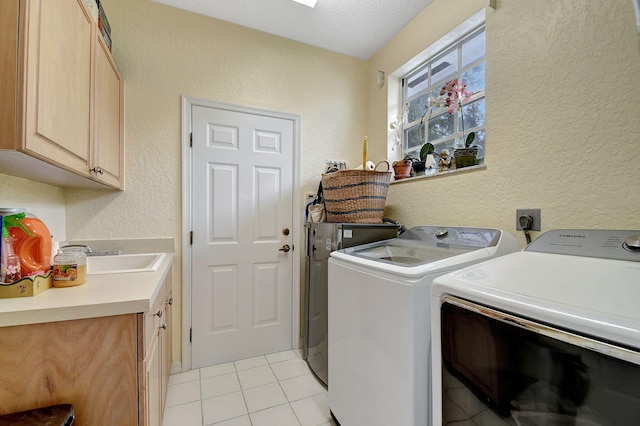 clothes washing area featuring light tile patterned flooring, cabinet space, a textured wall, and washing machine and clothes dryer