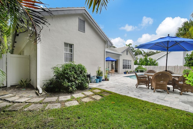 exterior space featuring stucco siding, fence, a lawn, and a patio