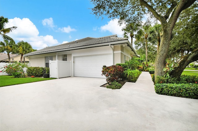 view of side of home with driveway, a garage, stucco siding, and a tiled roof