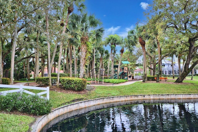 surrounding community featuring a playground, a lawn, and a water view