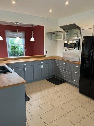 kitchen with gray cabinetry, pendant lighting, light tile patterned floors, and black appliances