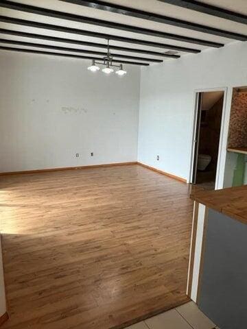 spare room featuring wood-type flooring and a notable chandelier