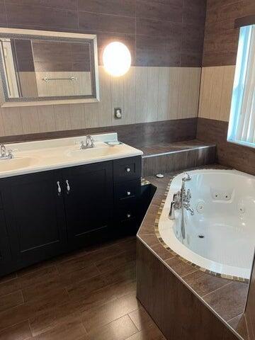 bathroom with tiled tub and vanity