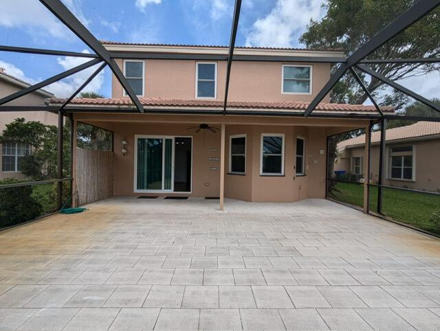 rear view of property featuring ceiling fan and glass enclosure