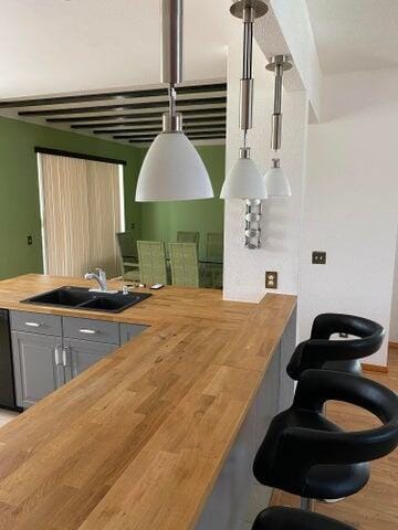 kitchen featuring gray cabinets, butcher block countertops, hardwood / wood-style flooring, and sink