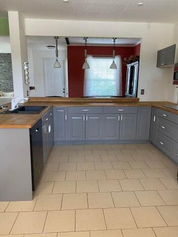 kitchen featuring pendant lighting, gray cabinets, and butcher block countertops