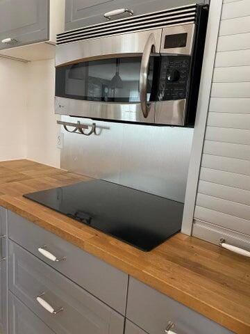 interior space featuring black electric cooktop, butcher block countertops, and gray cabinets