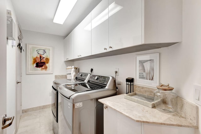 laundry room featuring cabinets, light tile patterned floors, and separate washer and dryer