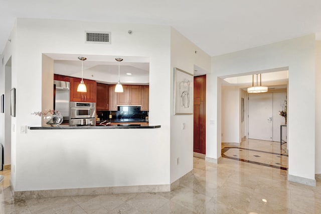 kitchen featuring pendant lighting, kitchen peninsula, appliances with stainless steel finishes, and backsplash