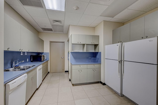 kitchen featuring a paneled ceiling, white appliances, sink, and light tile patterned flooring