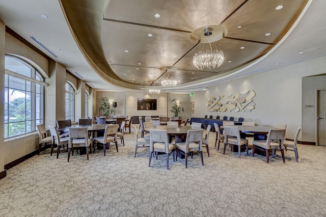 dining area with carpet, a notable chandelier, and a tray ceiling