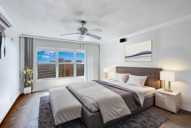 bedroom with crown molding, dark hardwood / wood-style floors, and ceiling fan