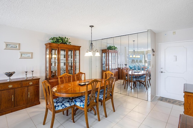 dining room with a textured ceiling, light tile patterned flooring, and an inviting chandelier