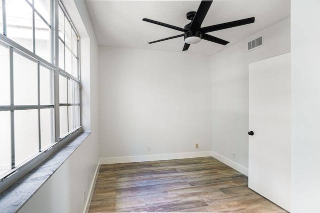 unfurnished room with a textured ceiling, plenty of natural light, ceiling fan, and hardwood / wood-style flooring